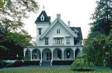 коттедж с белым фасадом и резным декором со стрельчатыми окнами на фронтоне